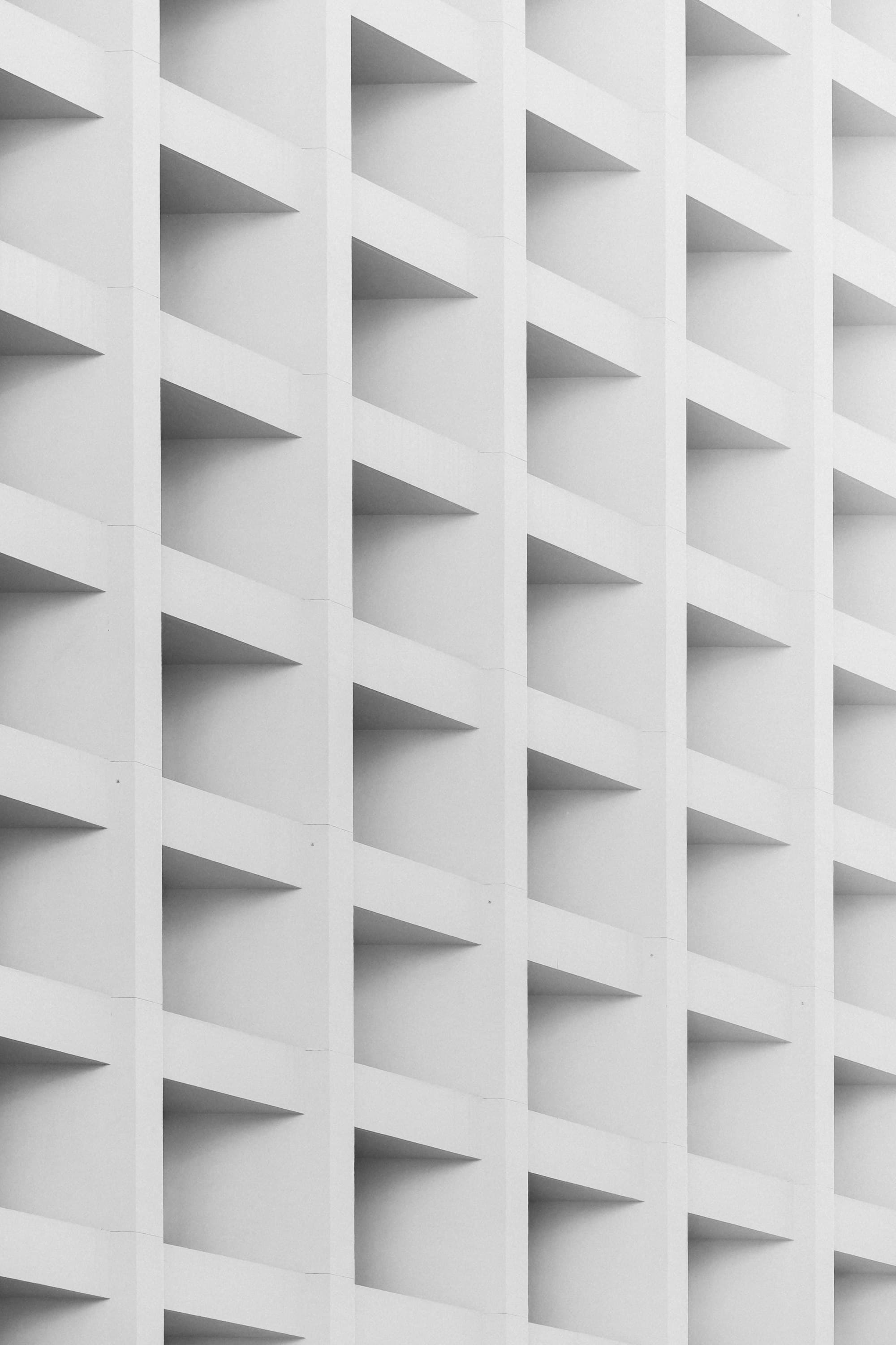 A white concrete facade with a regular pattern of deep, recessed window openings.