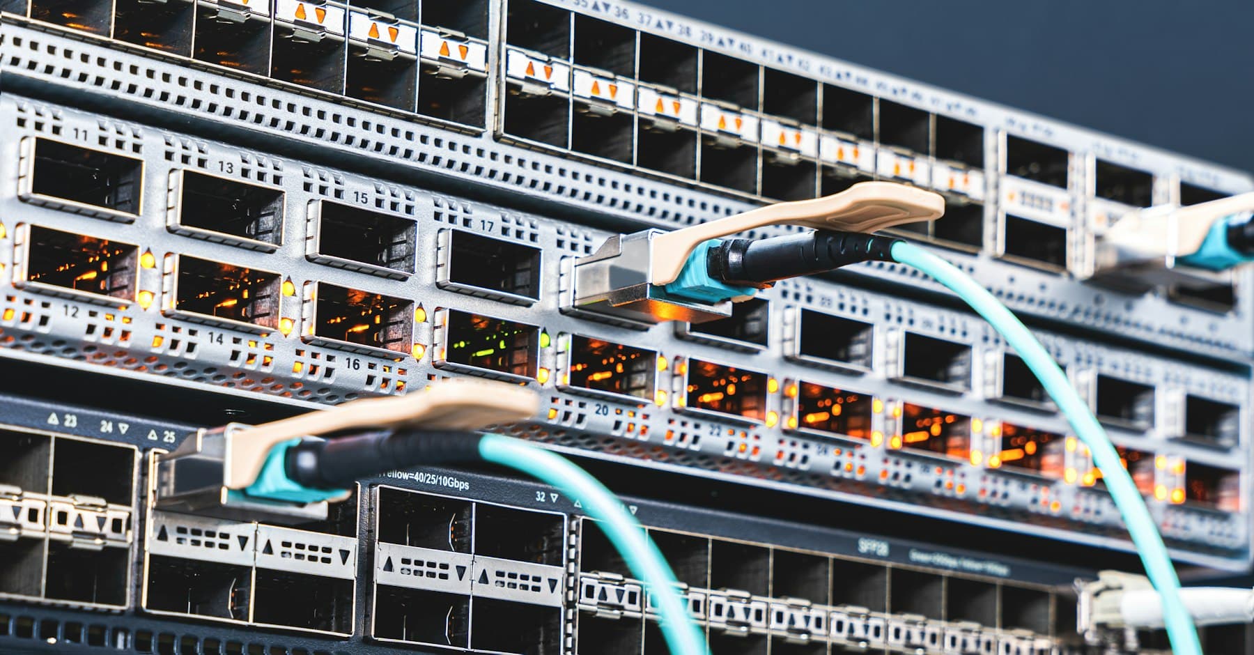 Close-up of a network switch with fibre-optic cables plugged into its ports.