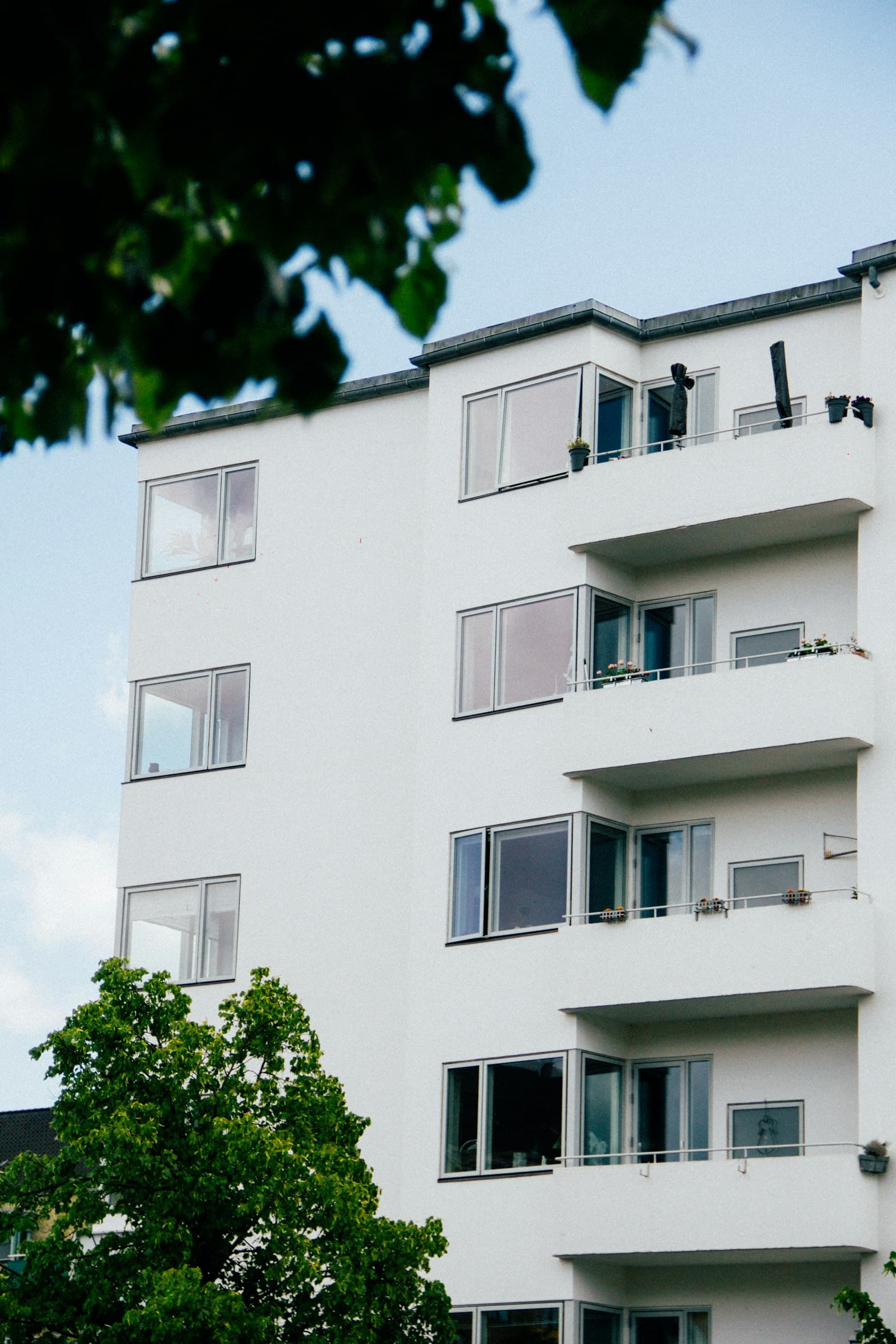 A white residential facade with balconies and large windows.
