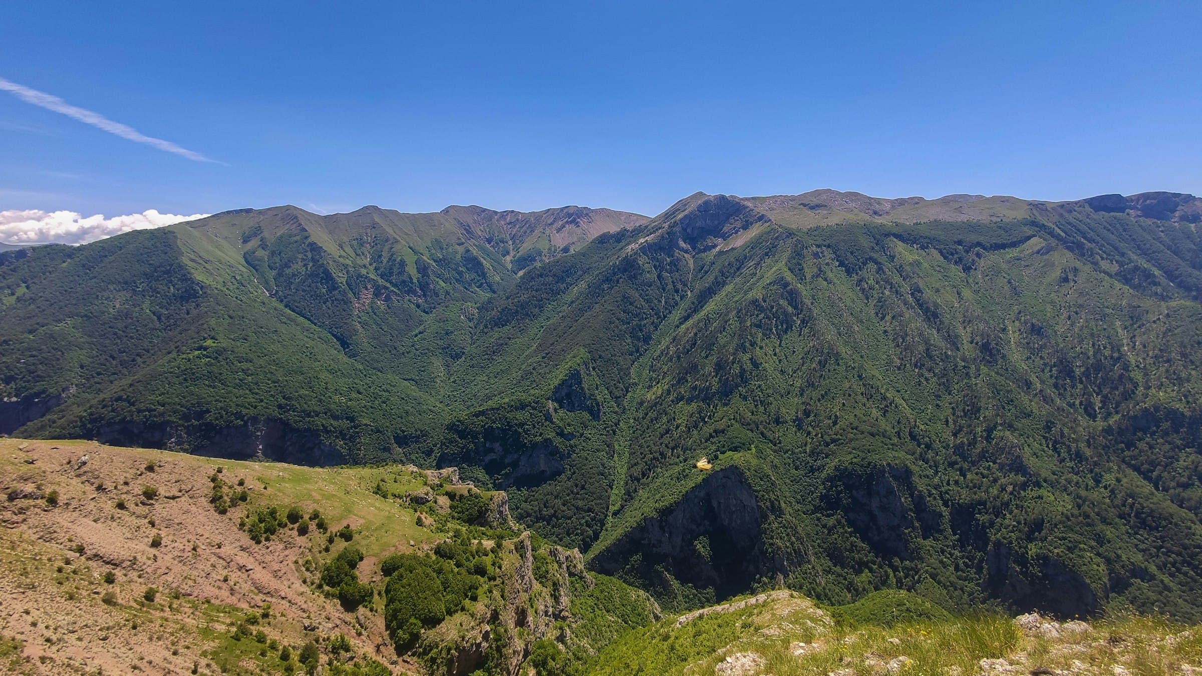 Layered green mountain ridges and valleys under a clear sky.